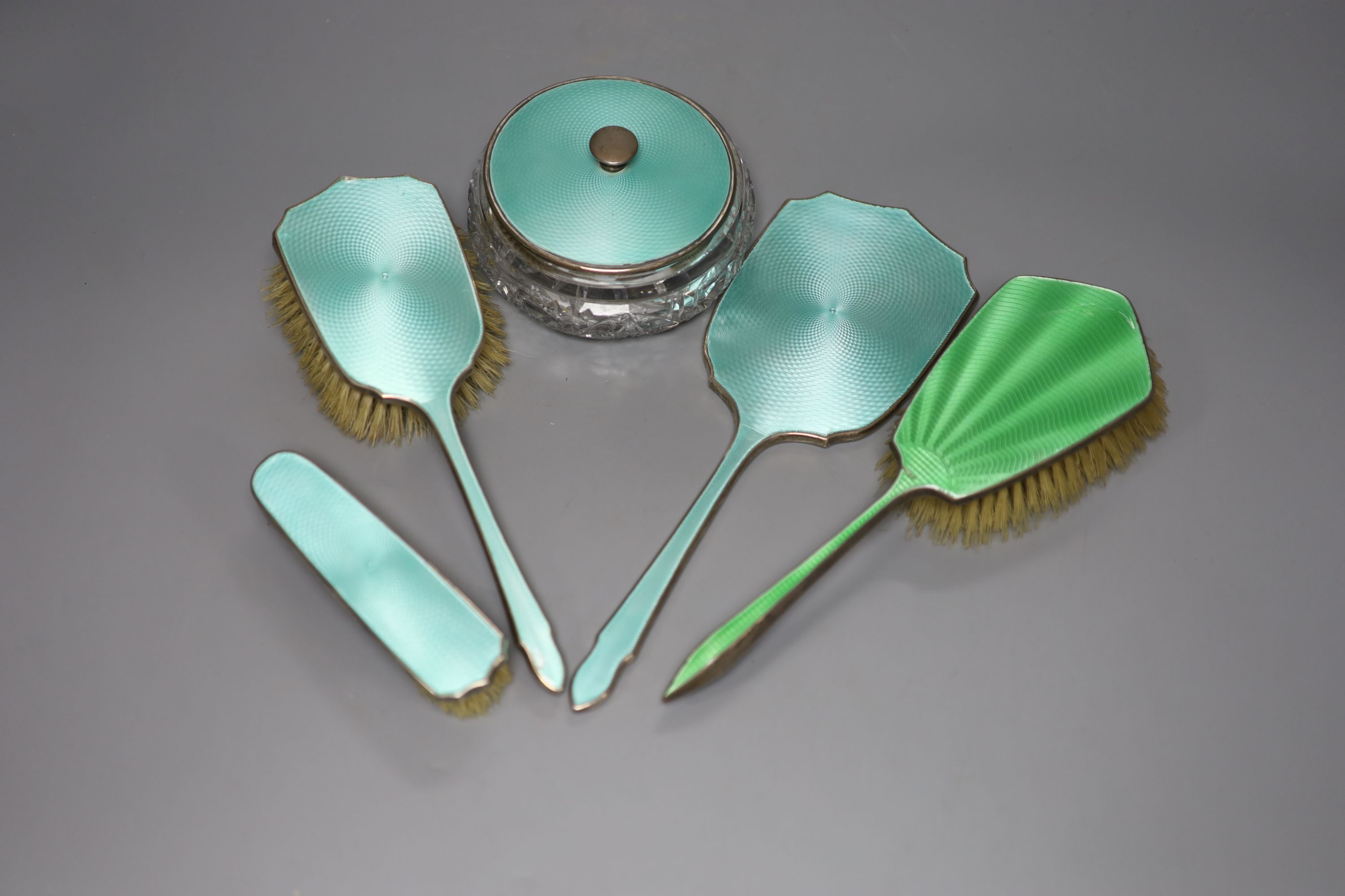 A 1930's silver and enamel toilet set including powder bowl, mirror and two brushes and one other silver & enamel brush.